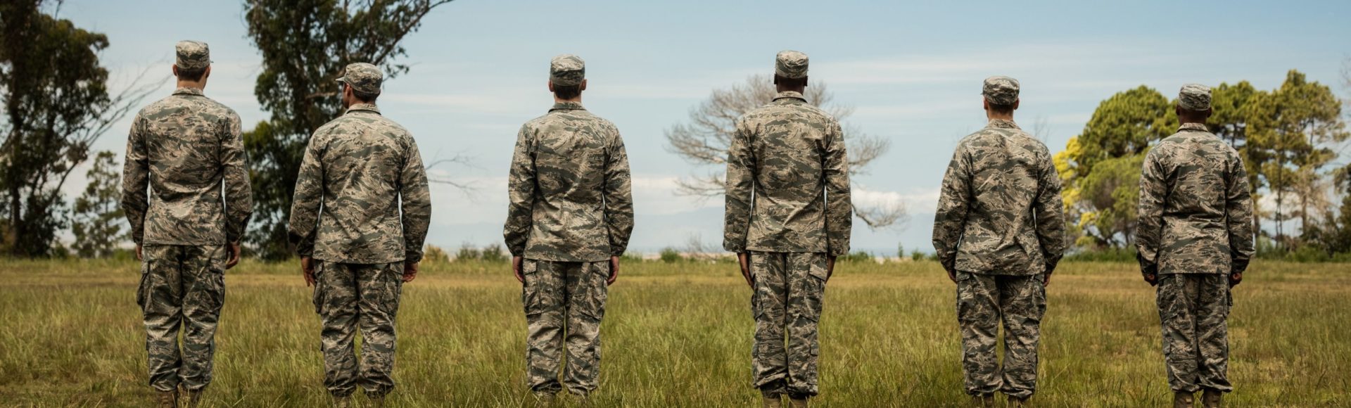 soldiers standing in a field looking away from the camera