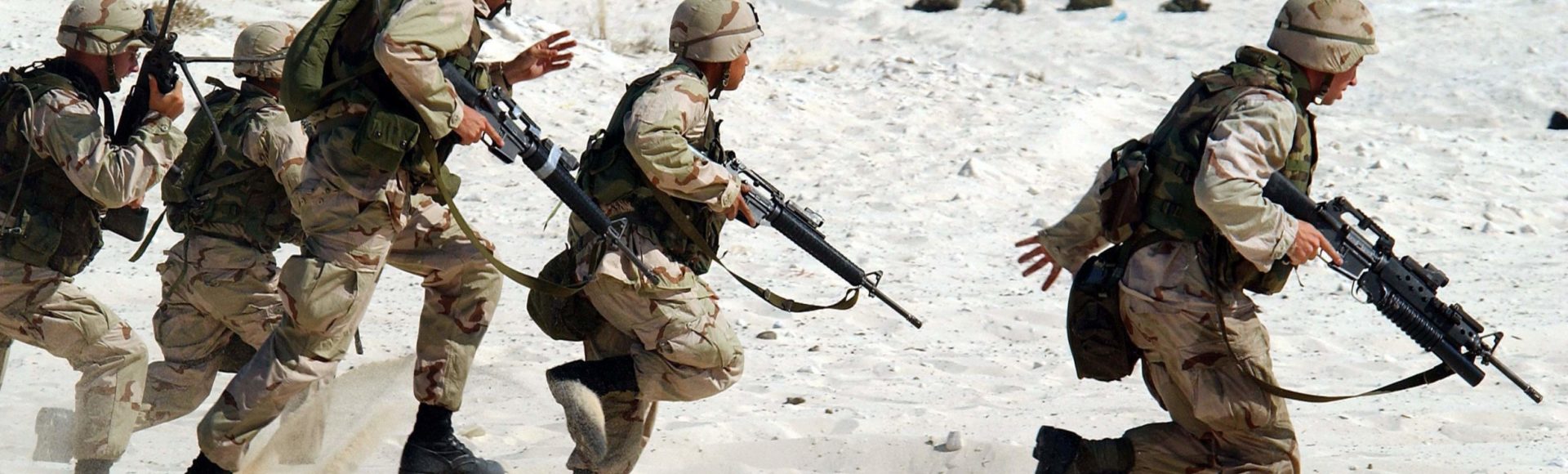 soldiers running with guns in full desert camouflage