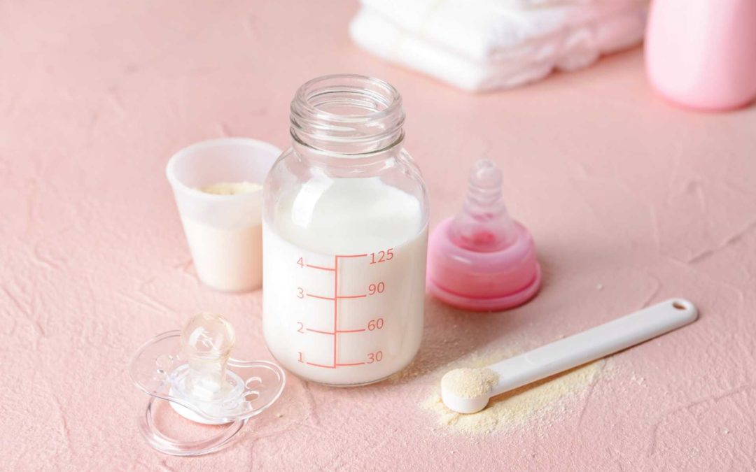 Pink floor with baby bottle, baby formula scoop, and towels.